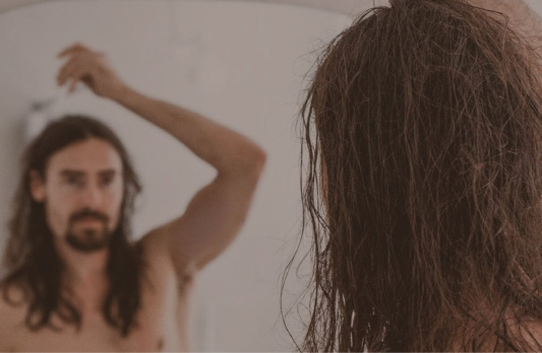 Man with long hair at a mirror