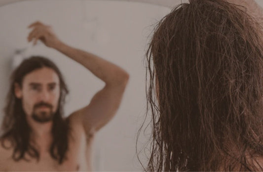 Man with long hair at a mirror